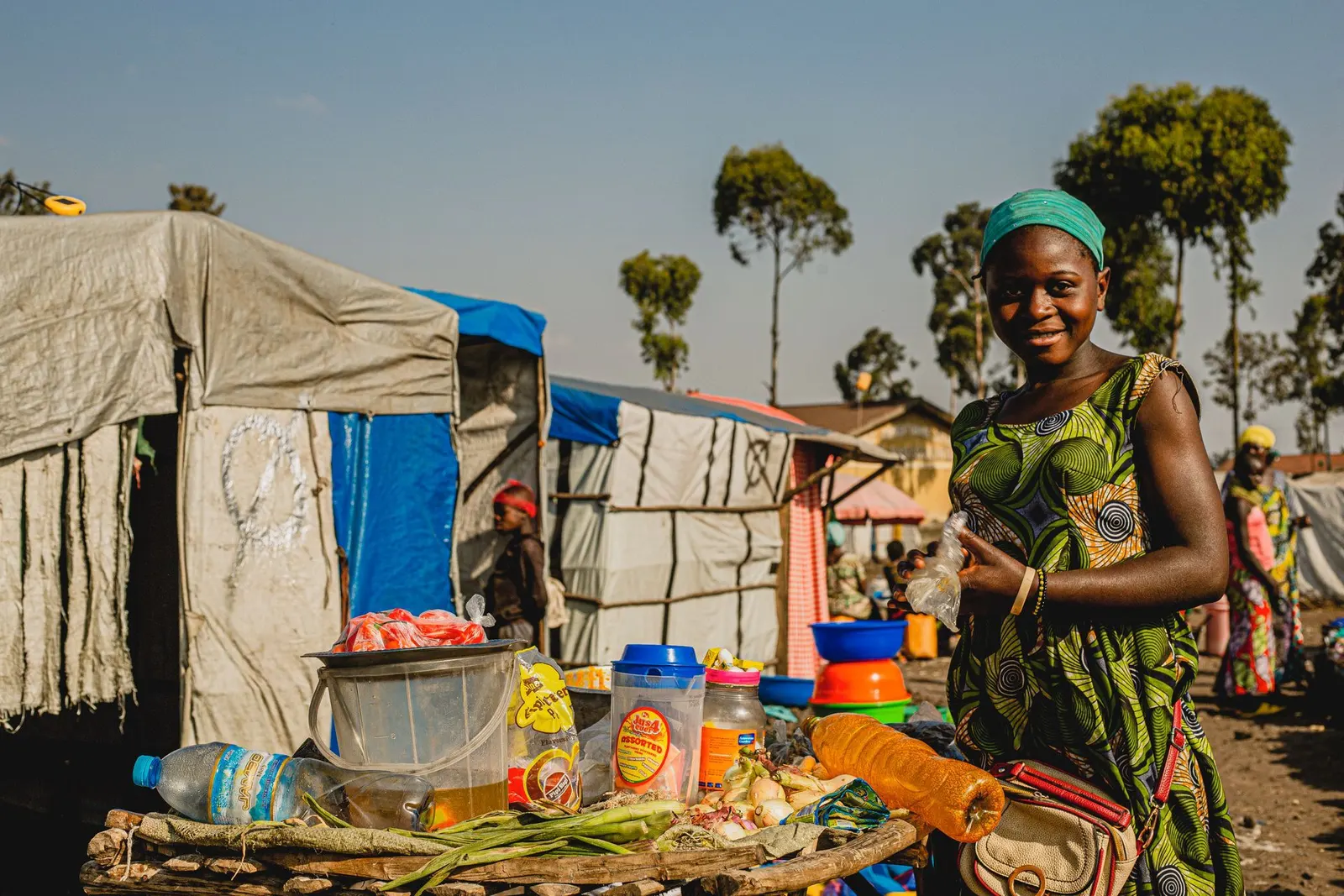 A cheerful woman standing at her colourful outdoor market stall.