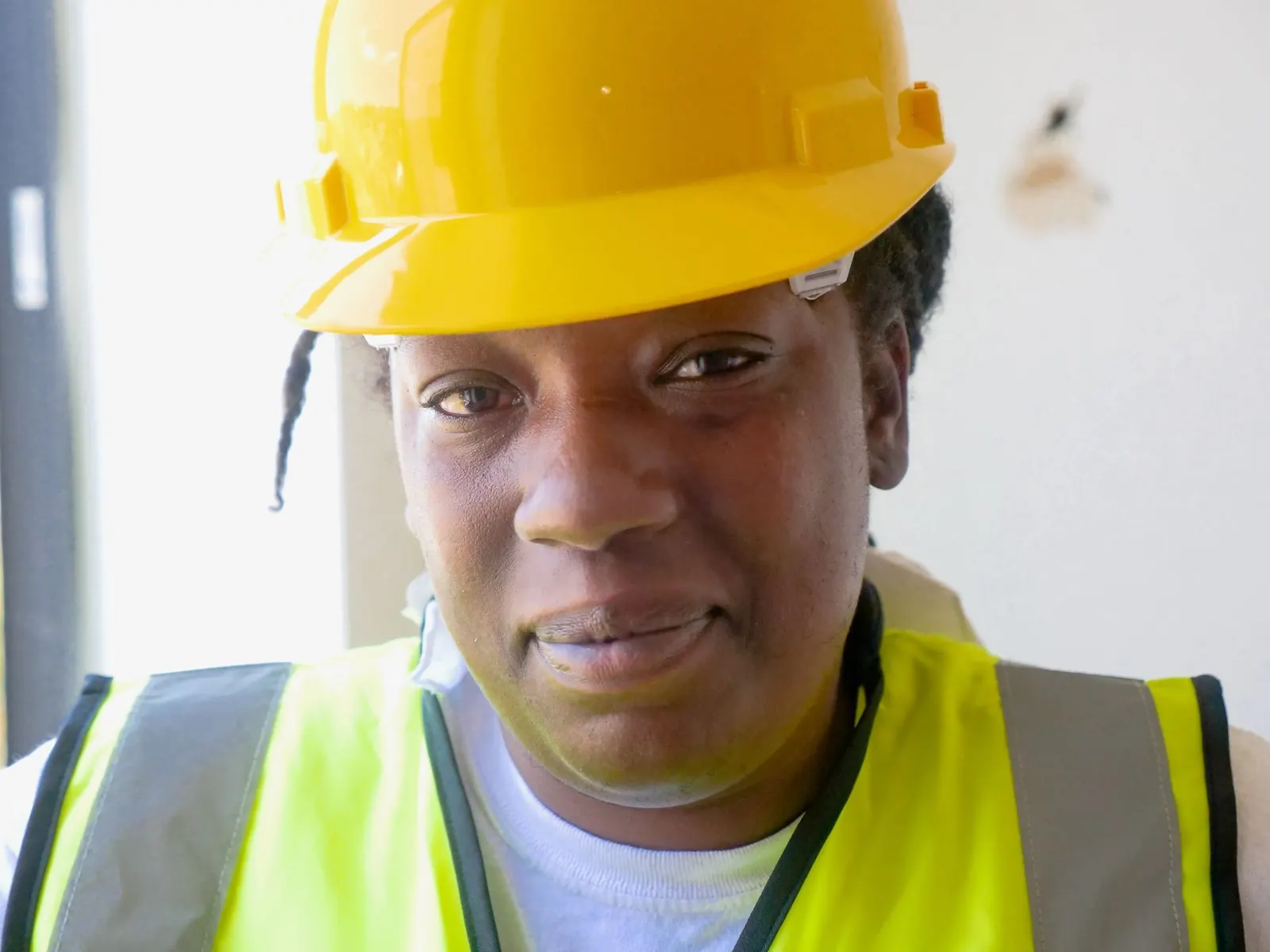 A female engineer in a yellow hard hat and safety vest.