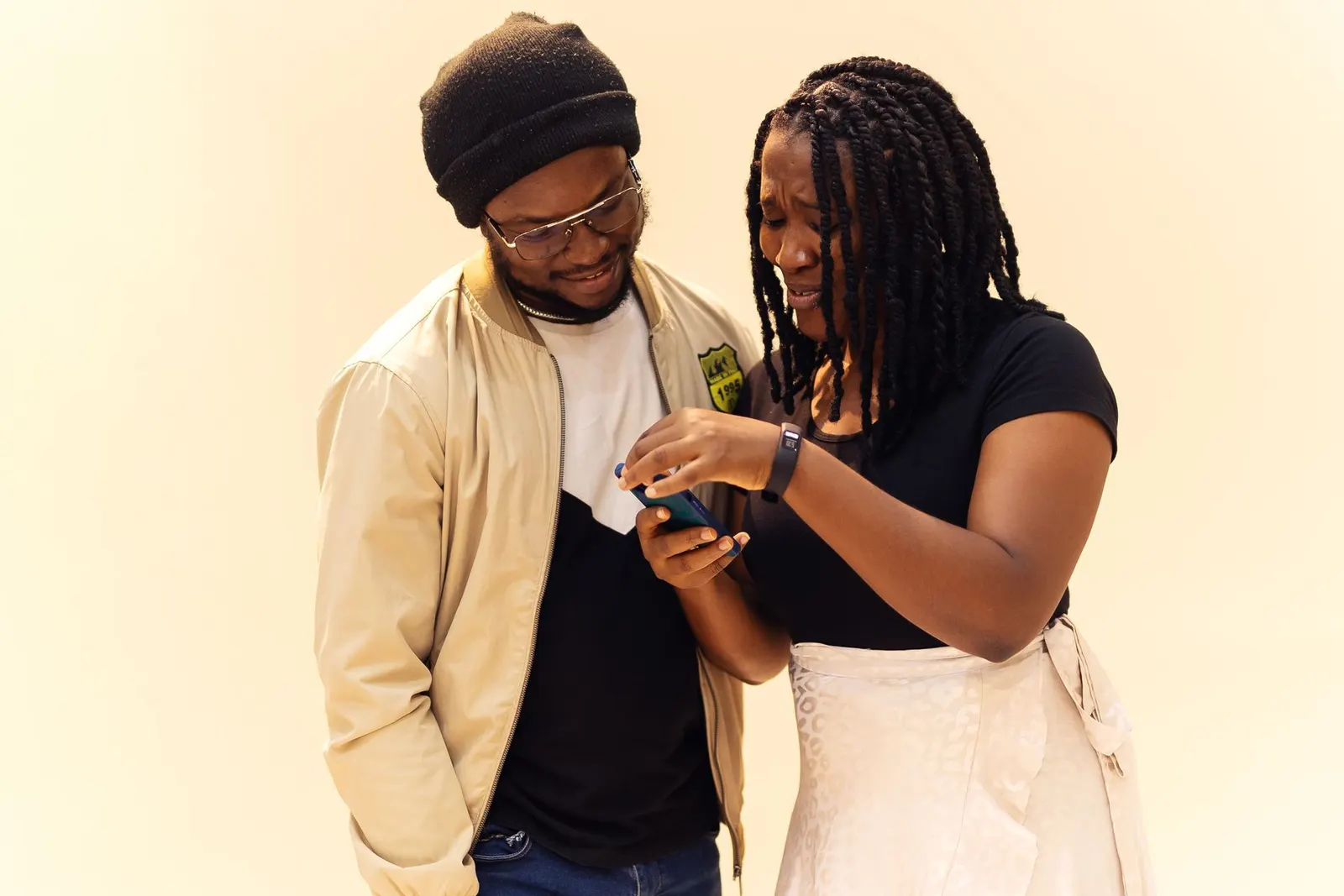 Two friends smiling as they look at a phone together.