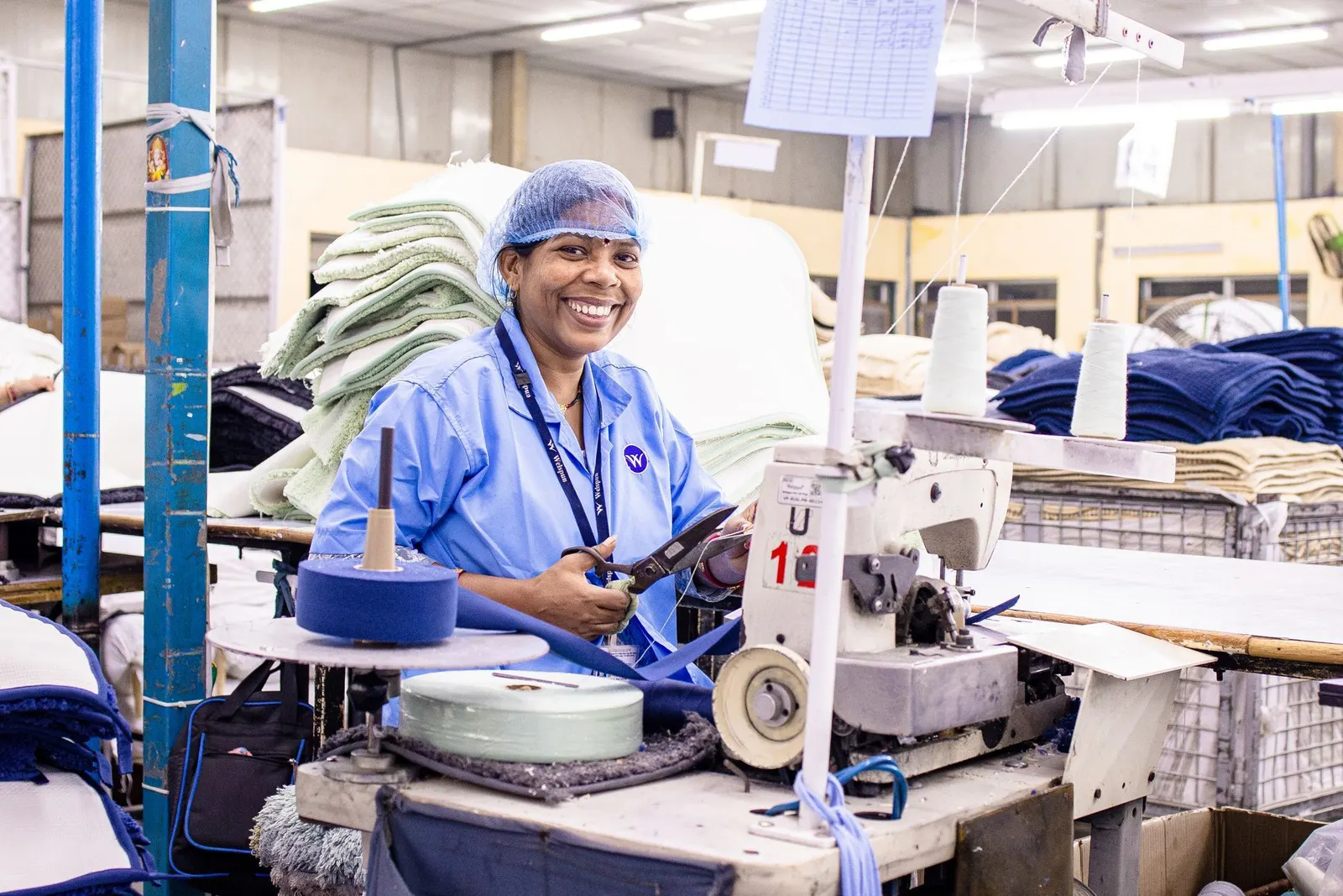 A smiling factory worker at her sewing machine.