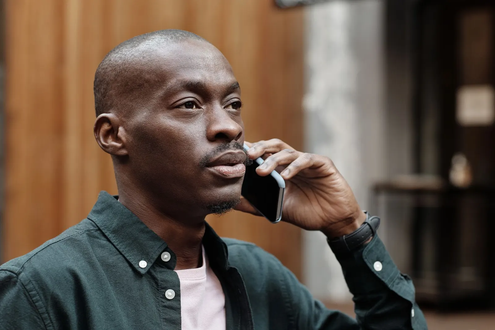A man in a green shirt talking on his phone.