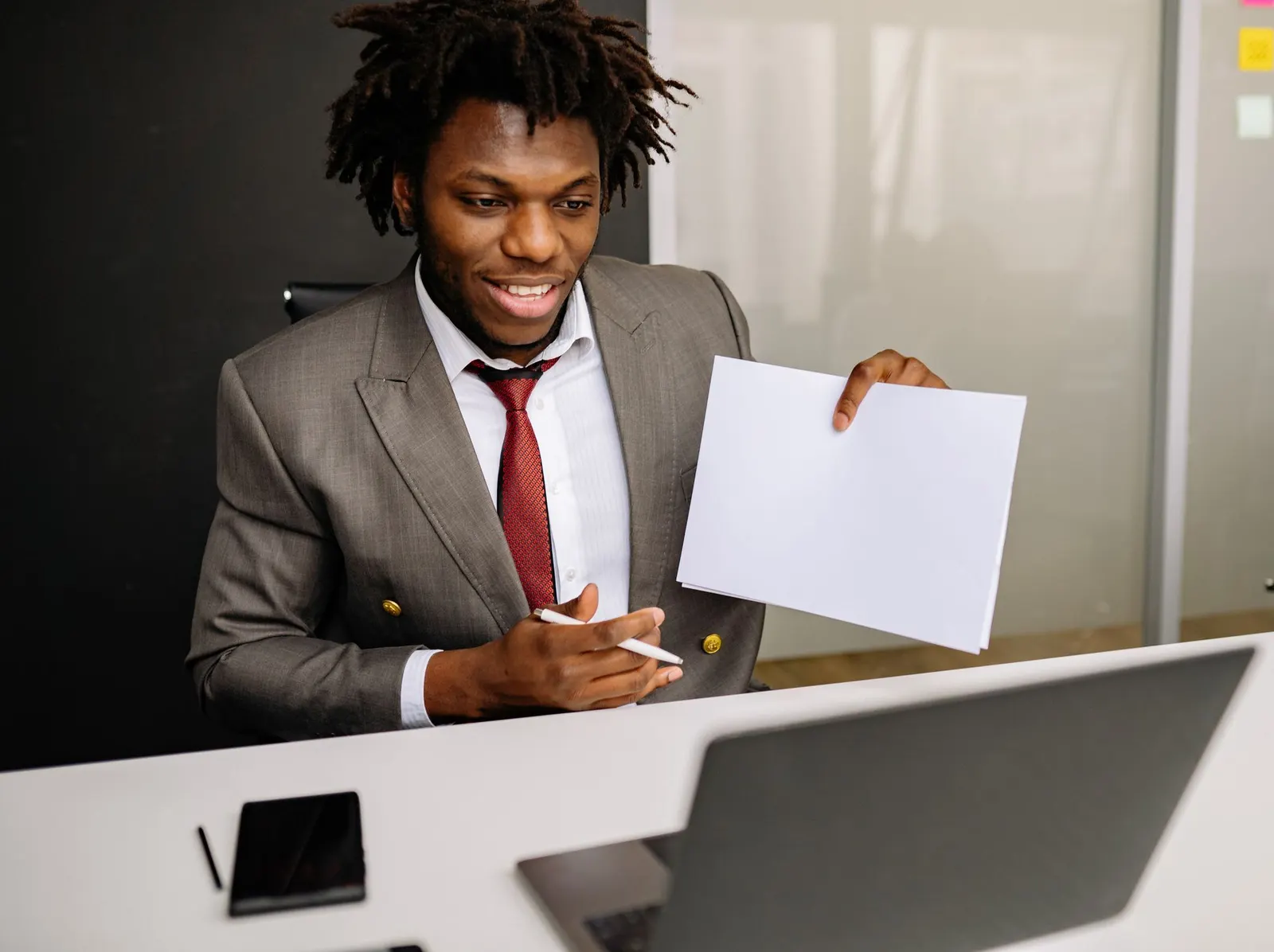 A man in a suit showing a document to people on a video call.